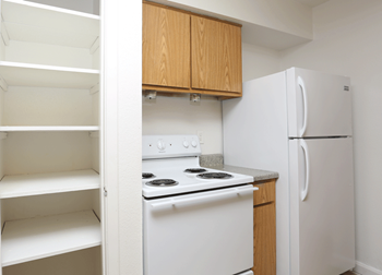 White fridge and stove with light wood cabinetry.  Pantry with multiple shelves.